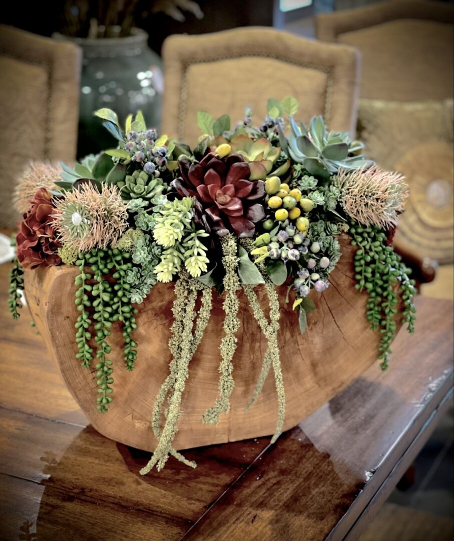 A wooden bowl filled with plants on top of a table.