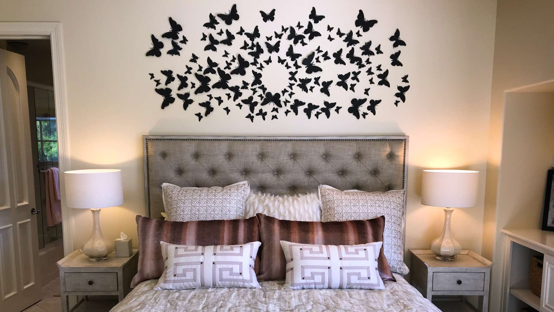 A bed with pillows and a wall of butterflies.