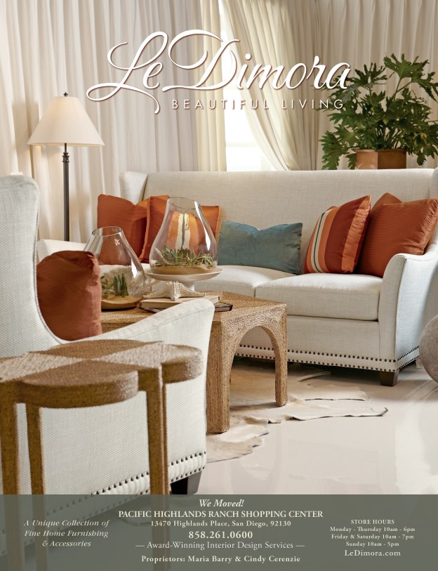 A living room with white furniture and orange pillows.