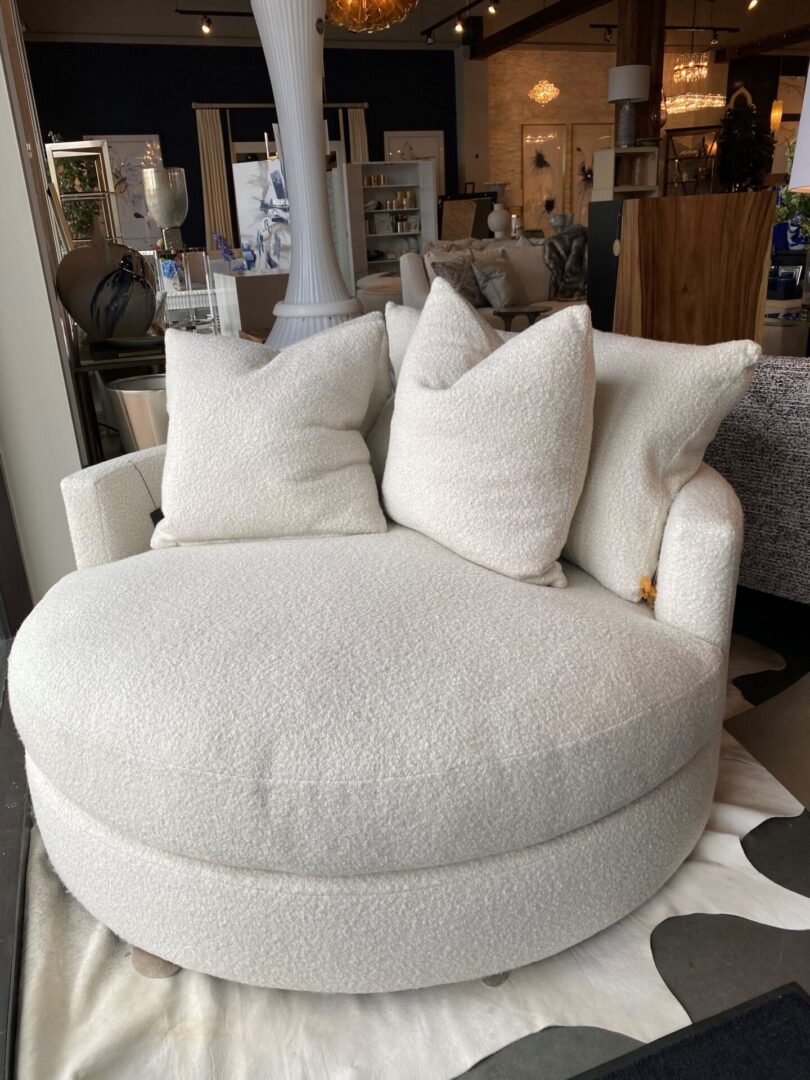 A white round chair with pillows on top of it.