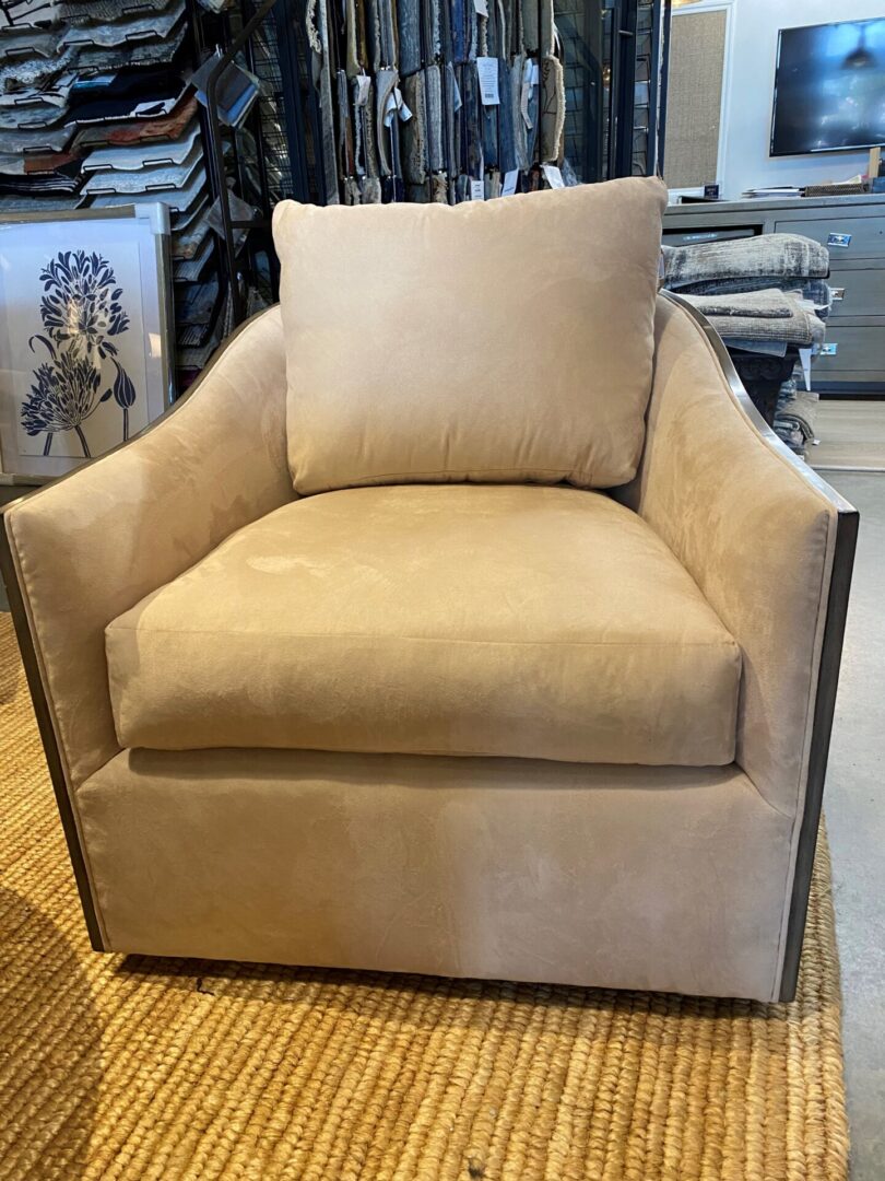 A beige chair with a brown trim and a pillow.